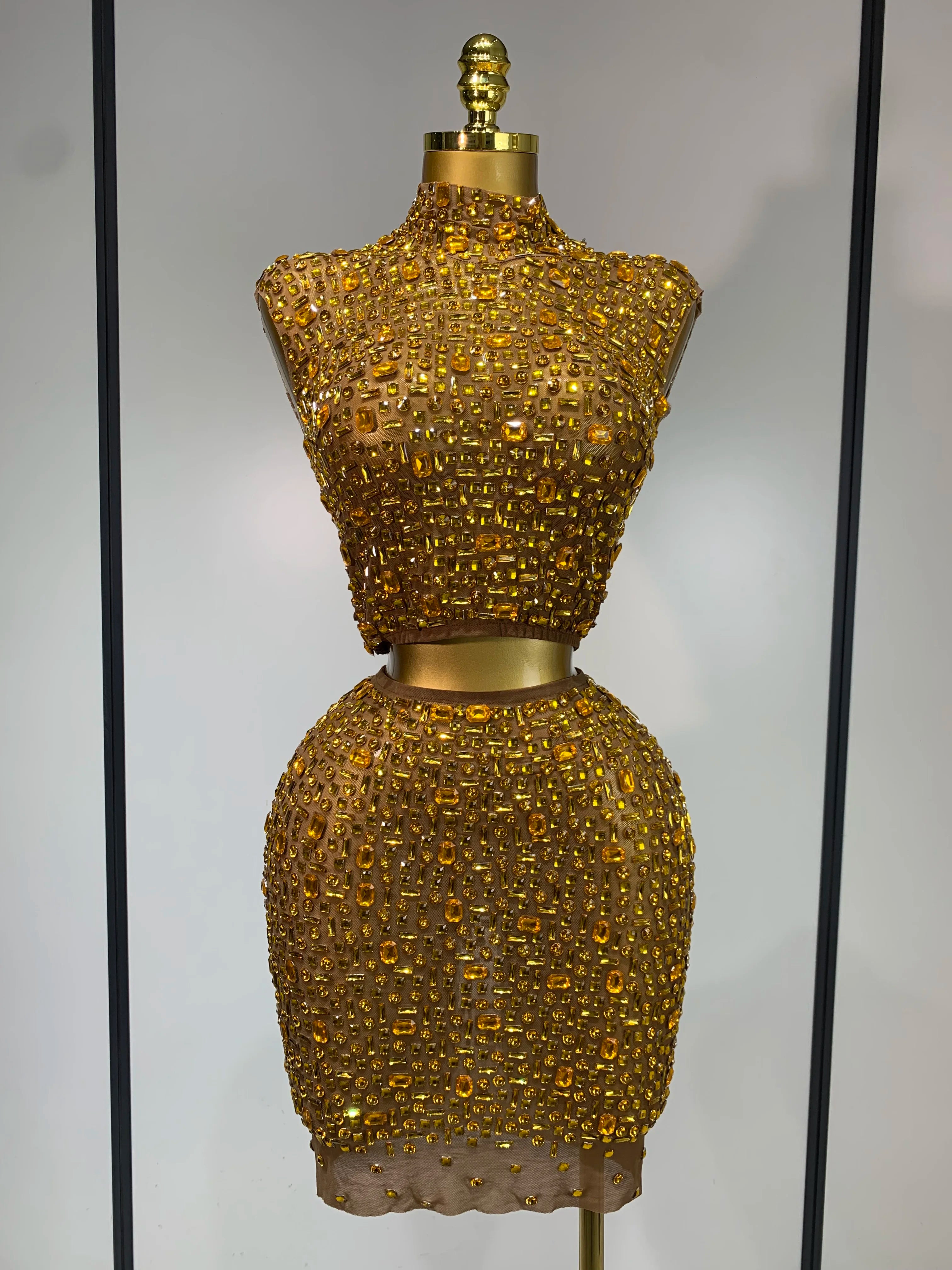 Gold beaded dress form against a neutral background