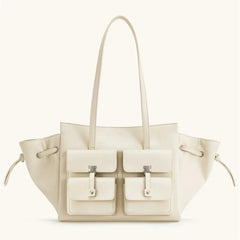 Beige handbag with two front pockets on a white background