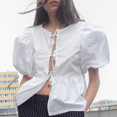 Person wearing a white blouse with puffed sleeves against an urban background