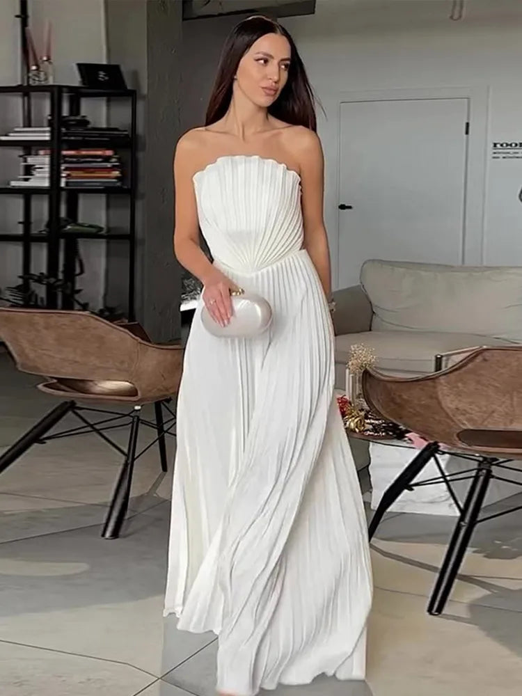 Woman in a white strapless dress holding a clutch in an indoor setting.