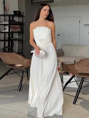 Woman in a white strapless dress holding a clutch in an indoor setting.