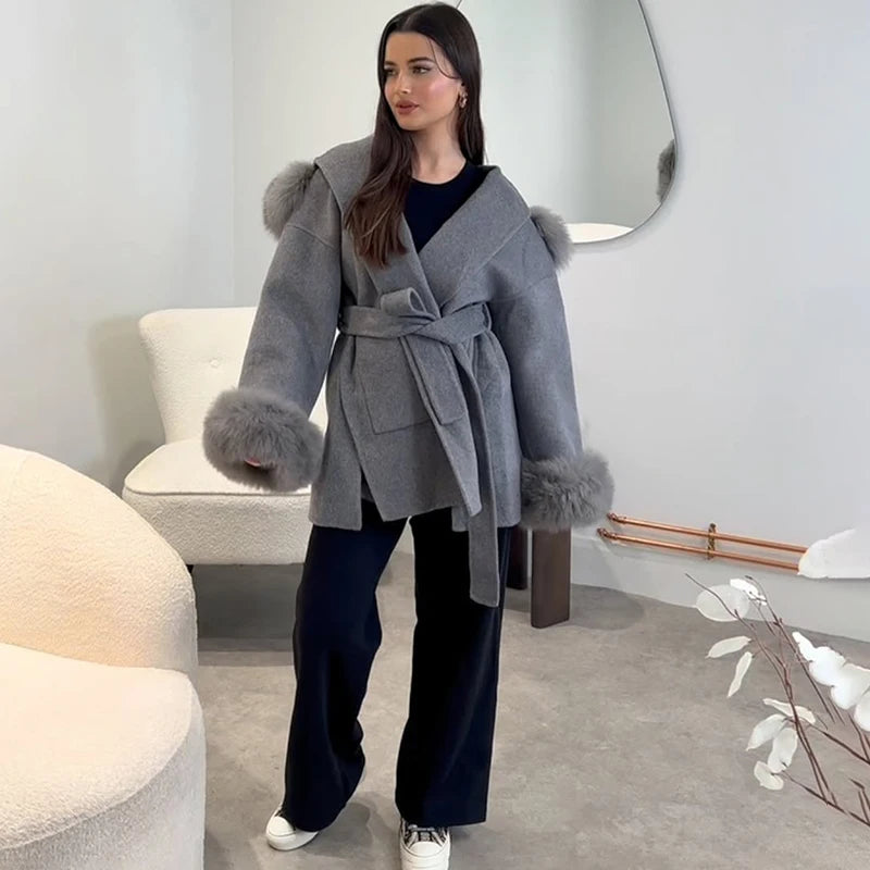 Woman wearing a gray coat with fur trim in a modern interior setting