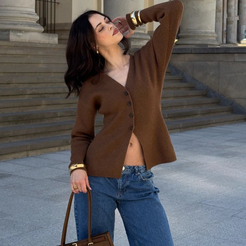 Woman in a brown cardigan and blue jeans standing on steps outdoors