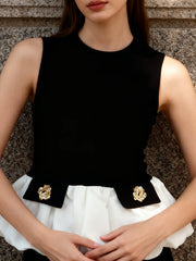 Woman wearing a black sleeveless top with gold accents