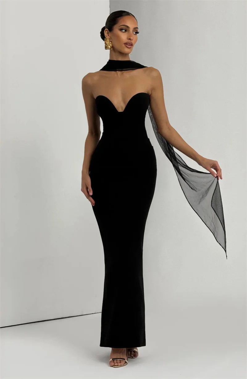 Woman wearing a black evening gown with a sheer overlay against a white background