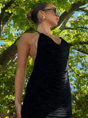 Woman in a black dress standing outdoors with trees in the background