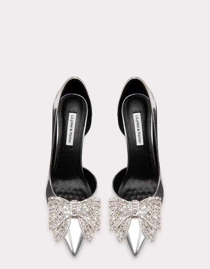 Black high-heeled shoes with silver bow designs on a white background