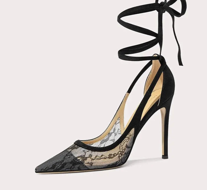 Black high-heeled shoe with lace detailing and tied ankle straps on a white background