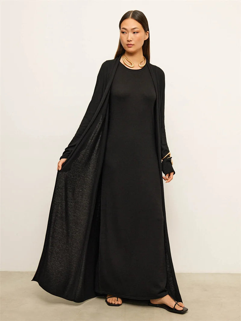 Woman wearing a black long-sleeve dress with a matching shawl against a white background