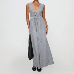 Woman wearing a long striped dress holding a black bag on a white background