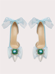 Light blue high-heeled shoes with large bows and decorative elements on a white background