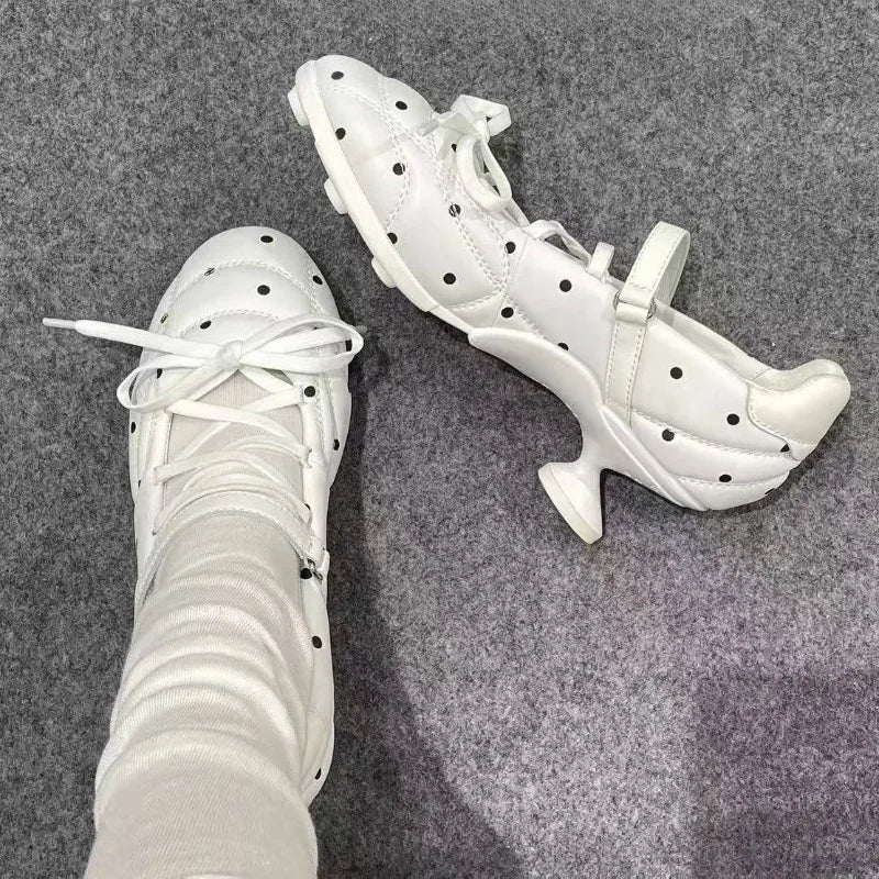 White polka dot Mary Jane heels and a pair of black ones on a grey carpet.
