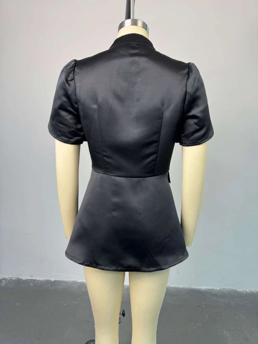 Black satin dress on a mannequin against a plain background