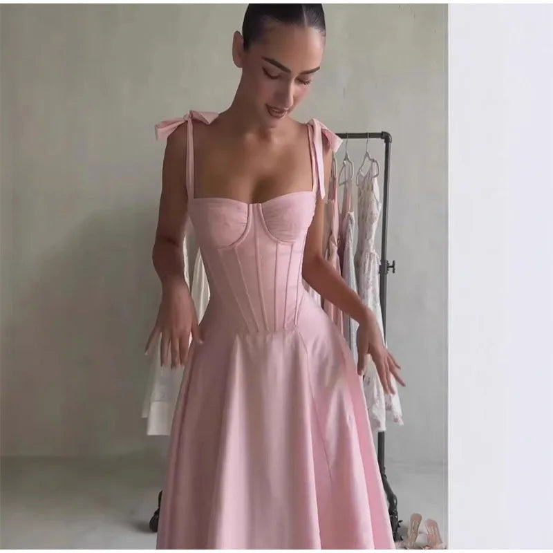 Woman wearing a pink dress with a fitted bodice and flowing skirt.