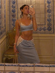 Selfie of woman in a light blue lace-trimmed crop top and midi skirt set in a tiled bathroom.