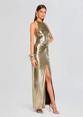 Woman wearing a gold halter neck gown with a high slit on a light gray background