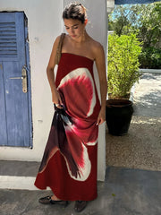 Woman wearing a red dress with white floral patterns outdoors.