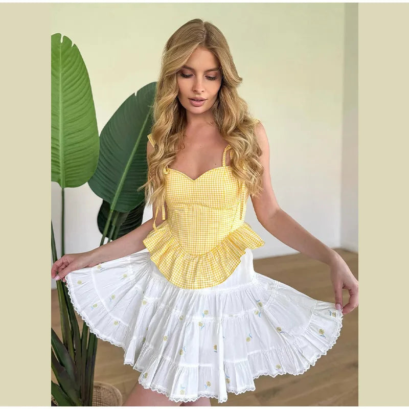 Woman wearing a yellow top and white skirt with ruffled layers, standing indoors.