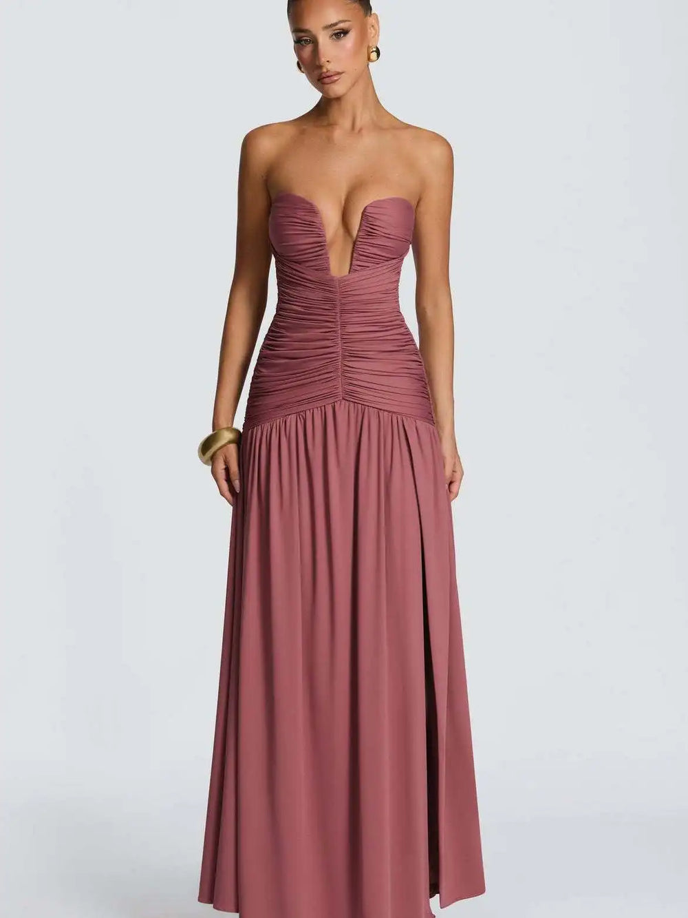 Woman wearing a strapless, long, mauve dress on a white background