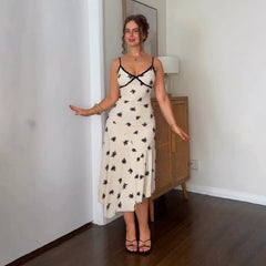 Woman wearing a white dress with black floral patterns in a room.
