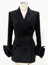 Sculpted double-breasted black blazer with dramatic floral cuffs shown on a mannequin.