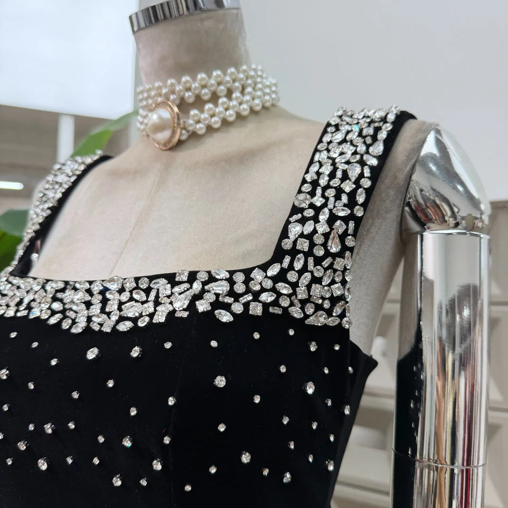 Mannequin wearing a black dress with silver embellishments and pearl necklace.
