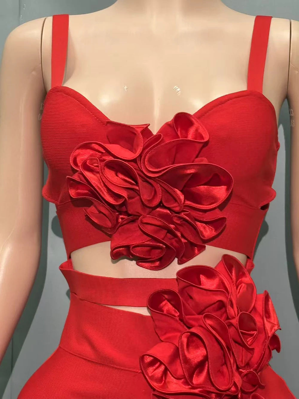 Red dress with floral embellishments on a mannequin against a gray background