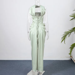 Light green dress on a mannequin against a white wall with a plant in the corner.