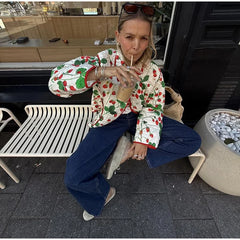 Woman in a colorful jacket sitting on a bench outdoors