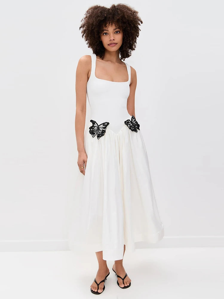 Woman wearing a white dress with black butterfly details on a white background