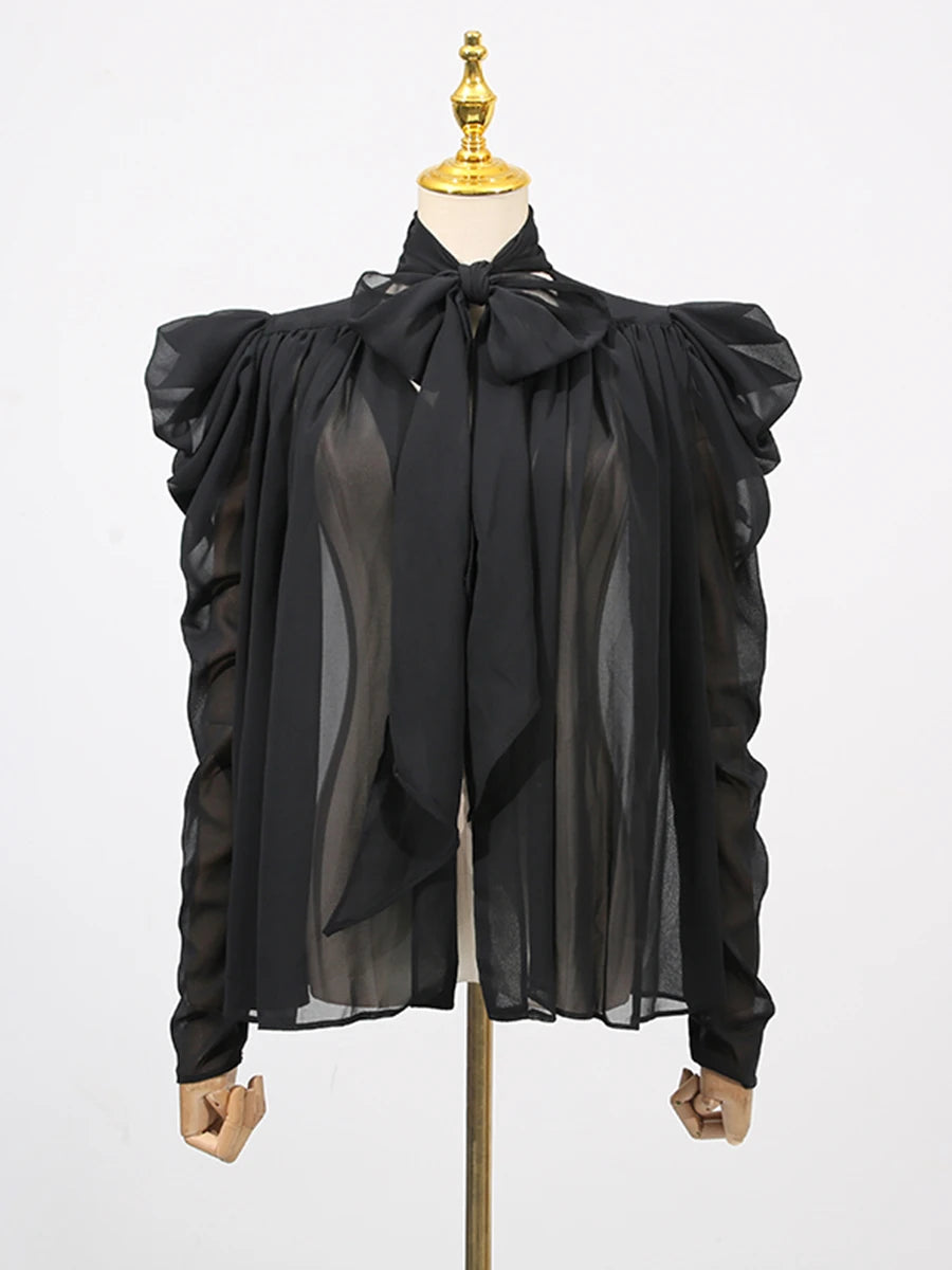 Black sheer blouse with ruffled sleeves on a mannequin against a white background