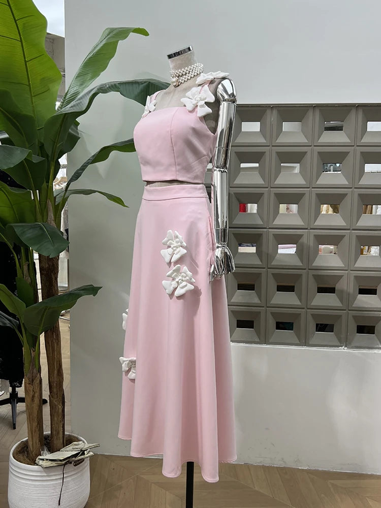 Pink dress with floral details on a mannequin against a geometric wall.
