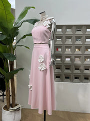 Pink dress with floral details on a mannequin against a geometric wall.