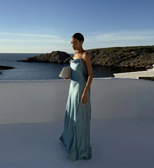 Woman in a light blue dress standing on a rooftop with ocean view