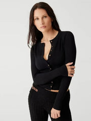 Woman wearing a black cardigan over a black top on a light gray background