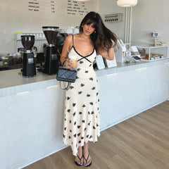 Woman in a white dress with black patterns standing in a coffee shop.