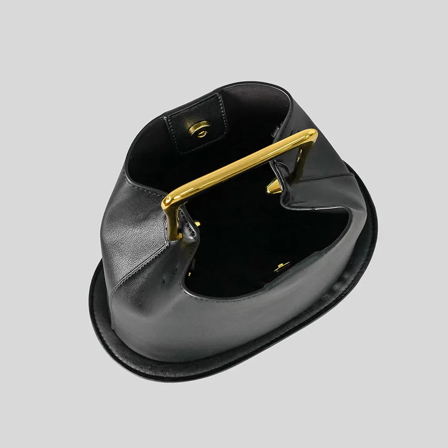 Black handbag with a gold clasp on a light gray background