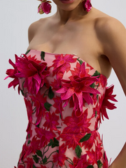 Woman wearing a strapless dress with pink floral embroidery on a plain background