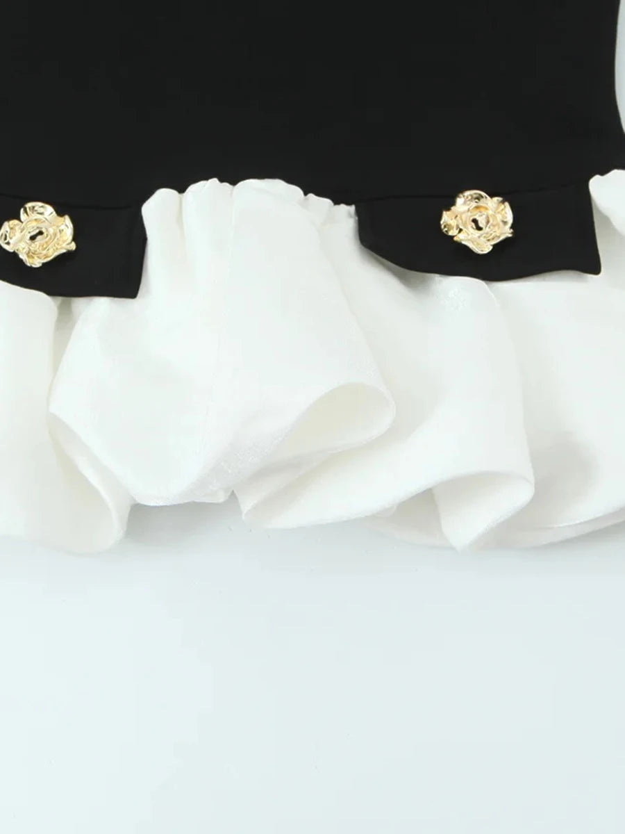 Close-up of a black and white garment with gold buttons on a light gray background