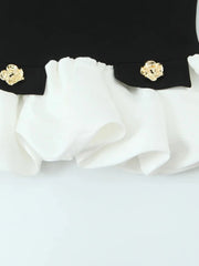 Close-up of a black and white garment with gold buttons on a light gray background