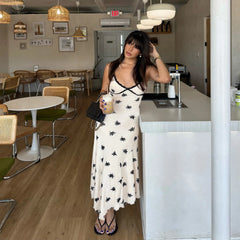 Woman in a white dress with black patterns standing in a modern cafe.