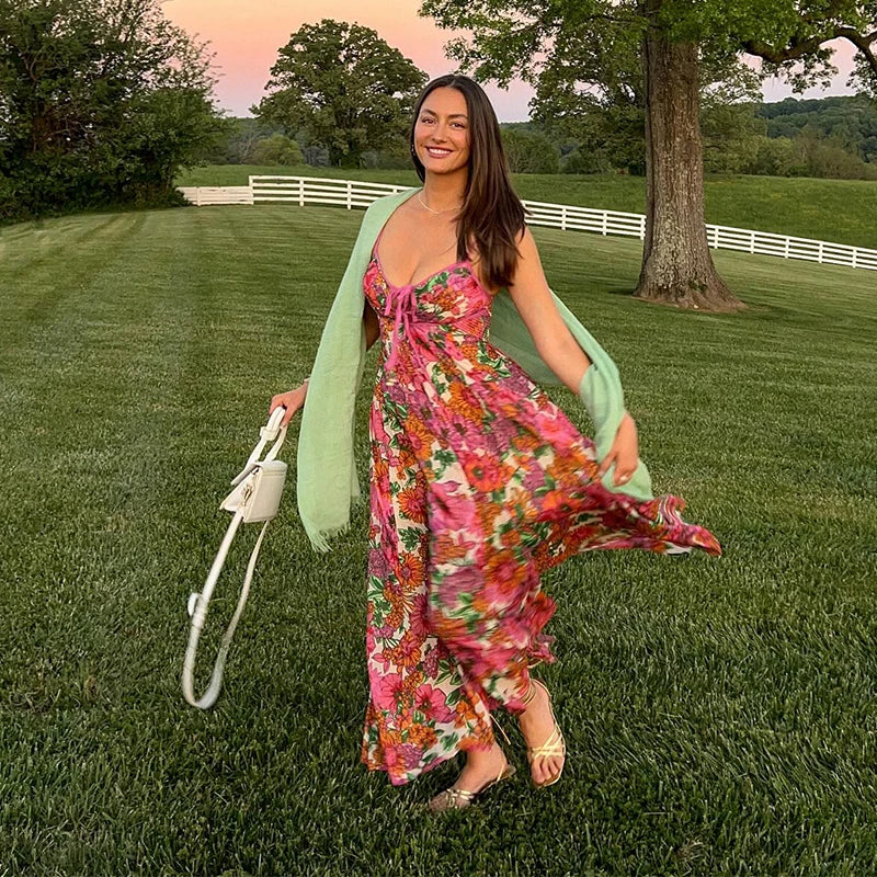 Woman in a floral dress standing on grass with a scenic background