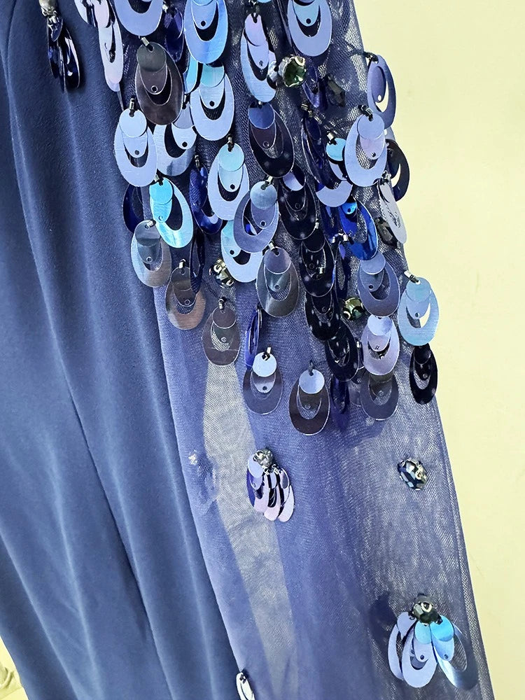 Close-up of a blue garment with decorative hanging elements on a yellow background