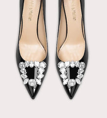Black high-heeled shoes with decorative heart-shaped embellishments on a light gray background