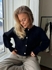 Woman wearing a dark blue cardigan sitting by a window