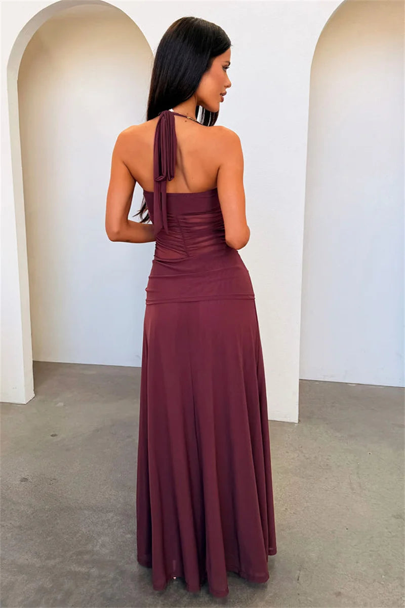 Woman wearing a long brown dress with a single shoulder strap in an indoor setting.