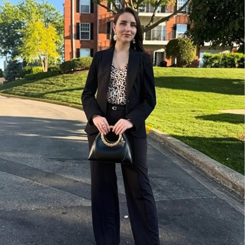 Woman holding a black sculptural handle top handle bag