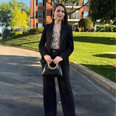 Woman holding a black sculptural handle top handle bag