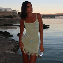 Woman in a light green dress with starfish patterns standing by a body of water.