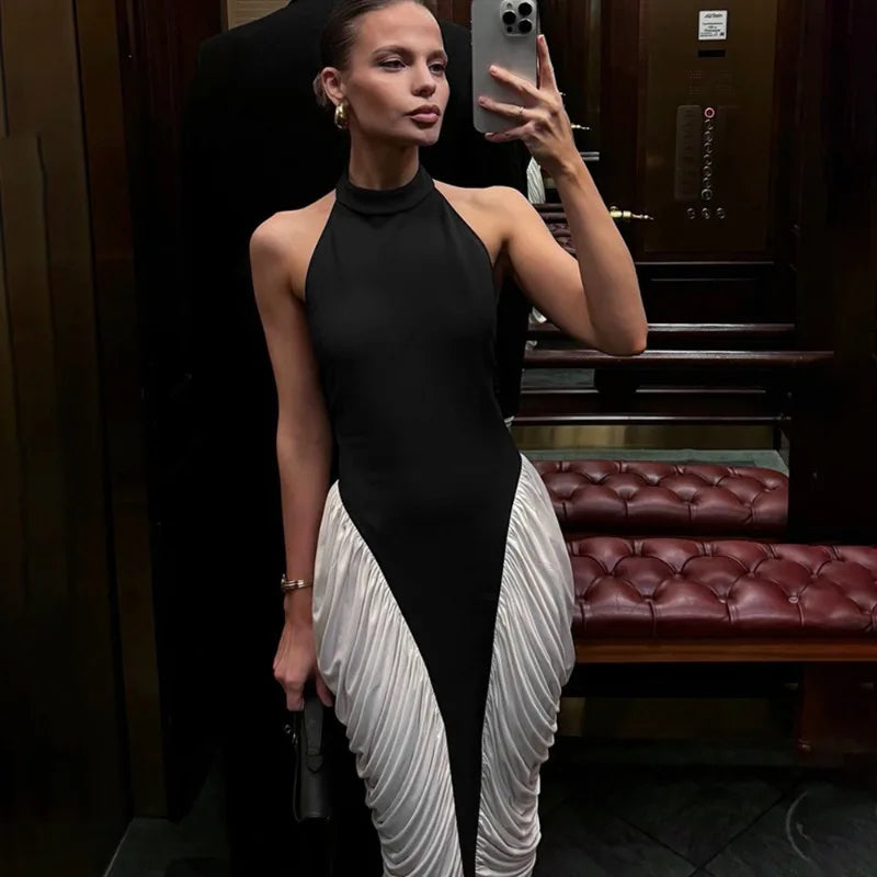 Woman taking a mirror selfie wearing a black and white dress in an indoor setting.